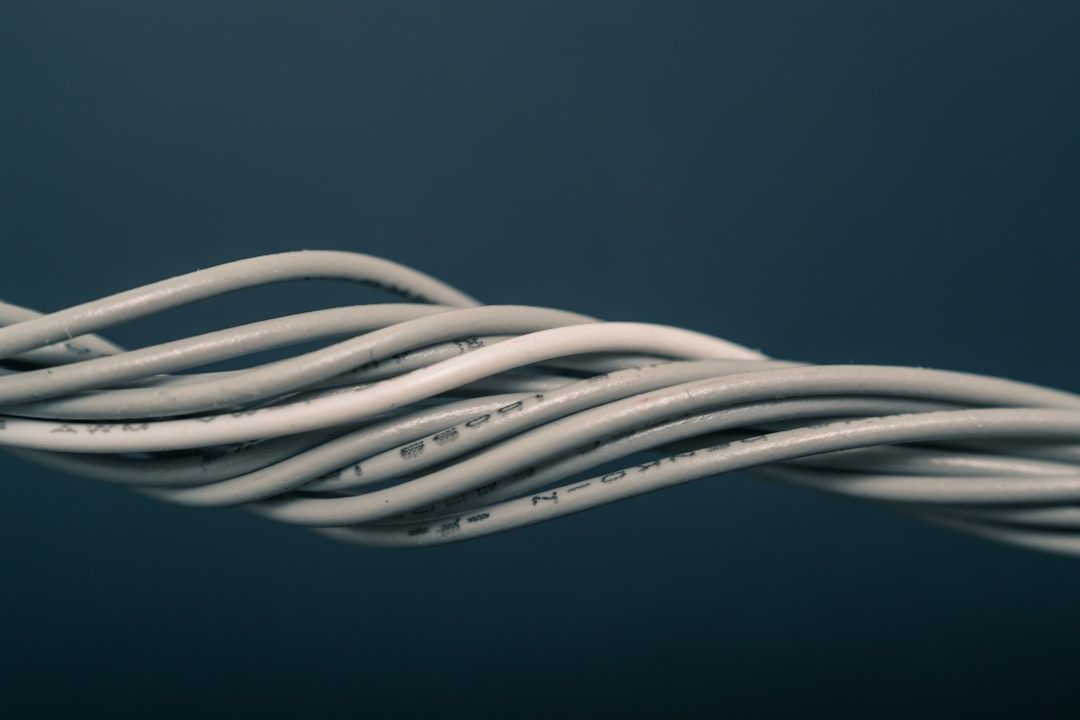 Mehrere miteinander verflochtene weiße Elektrokabel auf dunklem Hintergrund